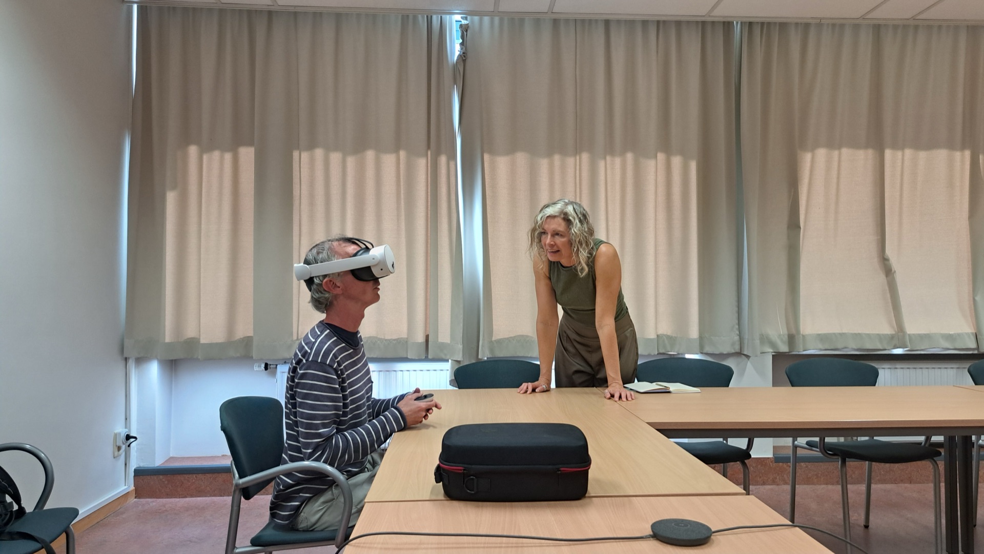 A participant wearing a VR headset while a trainer guides the session